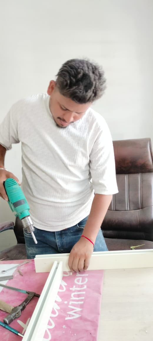 Worker drilling an aluminium window frame section